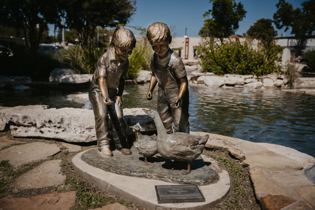 Statue of two kids and some ducks near a pond in Boerne, TX